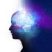 picture of the brain, glowing light blue, against the dark navy blue silhouette of a person dividing the picture in half, white and galaxy blue